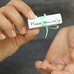 A rolled up note that says "Please open Me" on the outside. A form of craftivism that uses crafting.