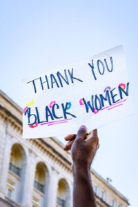 A sign saying Thank You Black Women being held up. New Year's Resolution for activism.