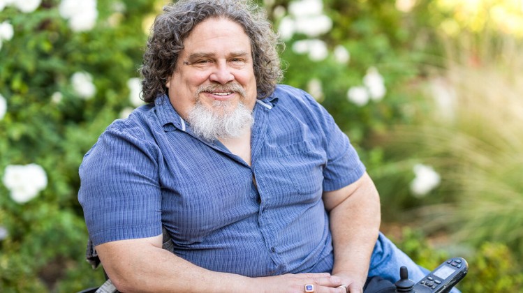 Jim LeBrecht, disability activist, in a blue shirt and smiling at the camera.