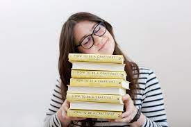 Craftivist Sarah Corbett with a pile of books.
