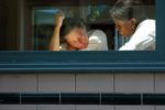 Woman speaking sad man, seen through an office wondow