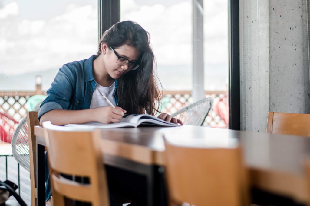 A female solo activist at a table studying a book. Motivational resources and learning opportunities for activists.
