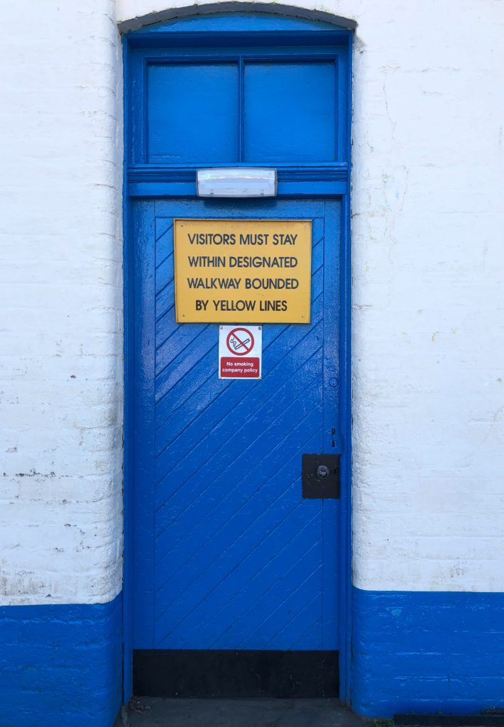 Blue door with a sign that reads Visitors must syat within bounds of yellowlines.