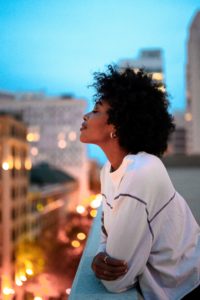 African American woman leaning on balcony overlooking city