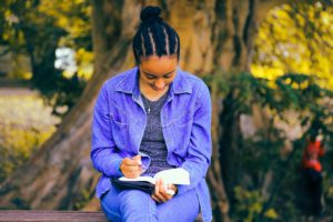 Young African American woman writing in her journal: the ultimate guide to journalling