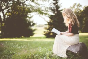 Woman with blond hair sitting outside studying the Bible