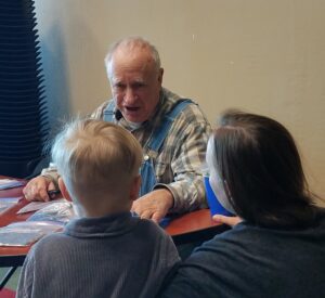 Master seed saver John Coykendall speaks to a mother and child at a seed swap, wild seeds
