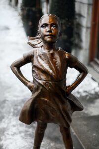 Fearless Girl sculpture in bronze. The girl has a determined look as she stares down the Wall Street bull. Remembrance Day.