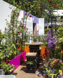 A balcony garden with arbors covered in flowers and leaves, a small seating area and a fish pond. From Chelsea Garden Show, The Cirrus Garden. Gardening in the city.