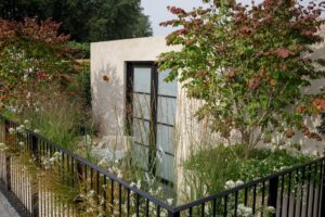 Balcony garden Chelsea Flower Show. Balcony of Blooms. Trees on each end and herbs growing in posts all around.