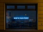 Large window with neon sign that says "What is your story"? Political spectrum.
