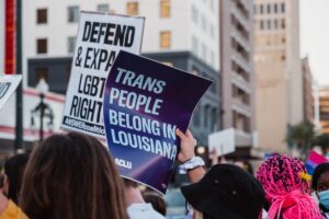 Protest with signs that say "Trans people belong in Louisiana" and "Defend LGBT Rights."