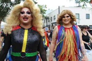 Two Pride queens wearing drag and smiling. LGBTQ+ awareness and education for allies.