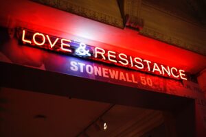 Red wall with white neon sign "Love and Resistance Stonewall 50."
