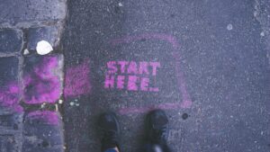 A pink chalk sign on the street that says "start here." How to get involved in activism. Making a difference in your community. Get started with activism. Potential activist resources.