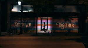 A man walks in front of art on a building that says "Stronger Together." AI and activism. Artificial intelligence in social change.