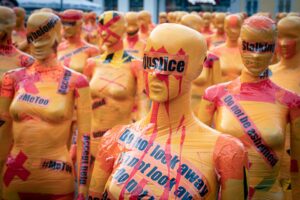 Art installation of woman covered by slogans about injustice, stalking, and MeToo. Privilege. Personal Power. wheel of power and privilege