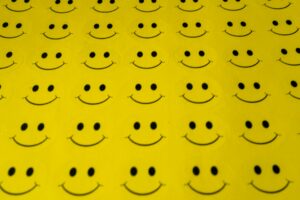 A pattern of Smiley faces on a yellow background stay motivated with effective activism strategies for beginners.