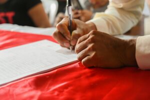 A man sitting at a table with a pen, signing a petition.