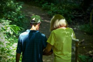 A woman and a senior citizen walk in the forest. She is working to change the world by making the outdoors accessible to senior citizens. Change the world and give your legacy meaning. Volunteer, give back, and be the change you wish to see in the world.