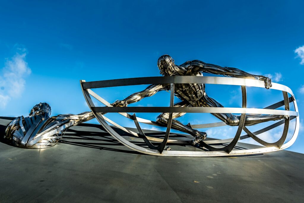 A metal sculture in which a personis reaching out to help another person. Change the World.