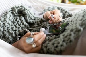 Picture of a phone in a personal's lap on top of a gray crocheted blanket. Ready for minfulness.