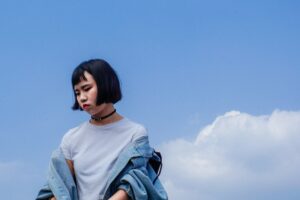 A female Asian teen with a bob looks down sadly.