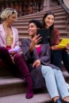Three young women sitting outdoors volunteering, Activism method, activism examples, activism types.