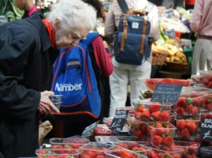 A woman shops at a farmer's market. The meaning of boycott. Buycotting.
