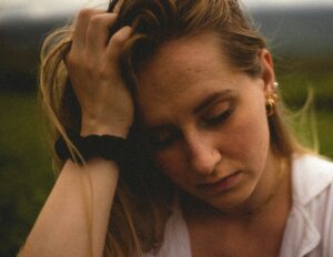 A sad woman grabs her hair and looks down, distressed. Equanimity means, the meaning of equanimity.