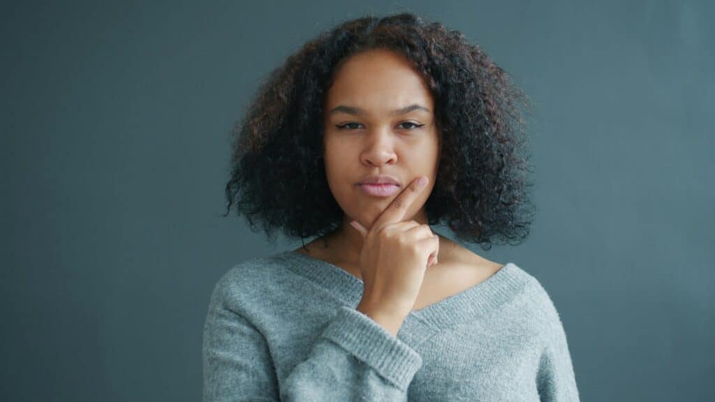 A Black woman in a gray sweater pondering the meaning of critical thinking